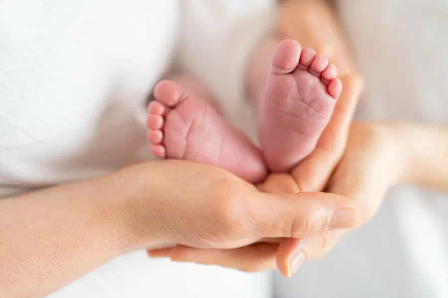 Babyfüsse in den Händen einer Erwachsenen