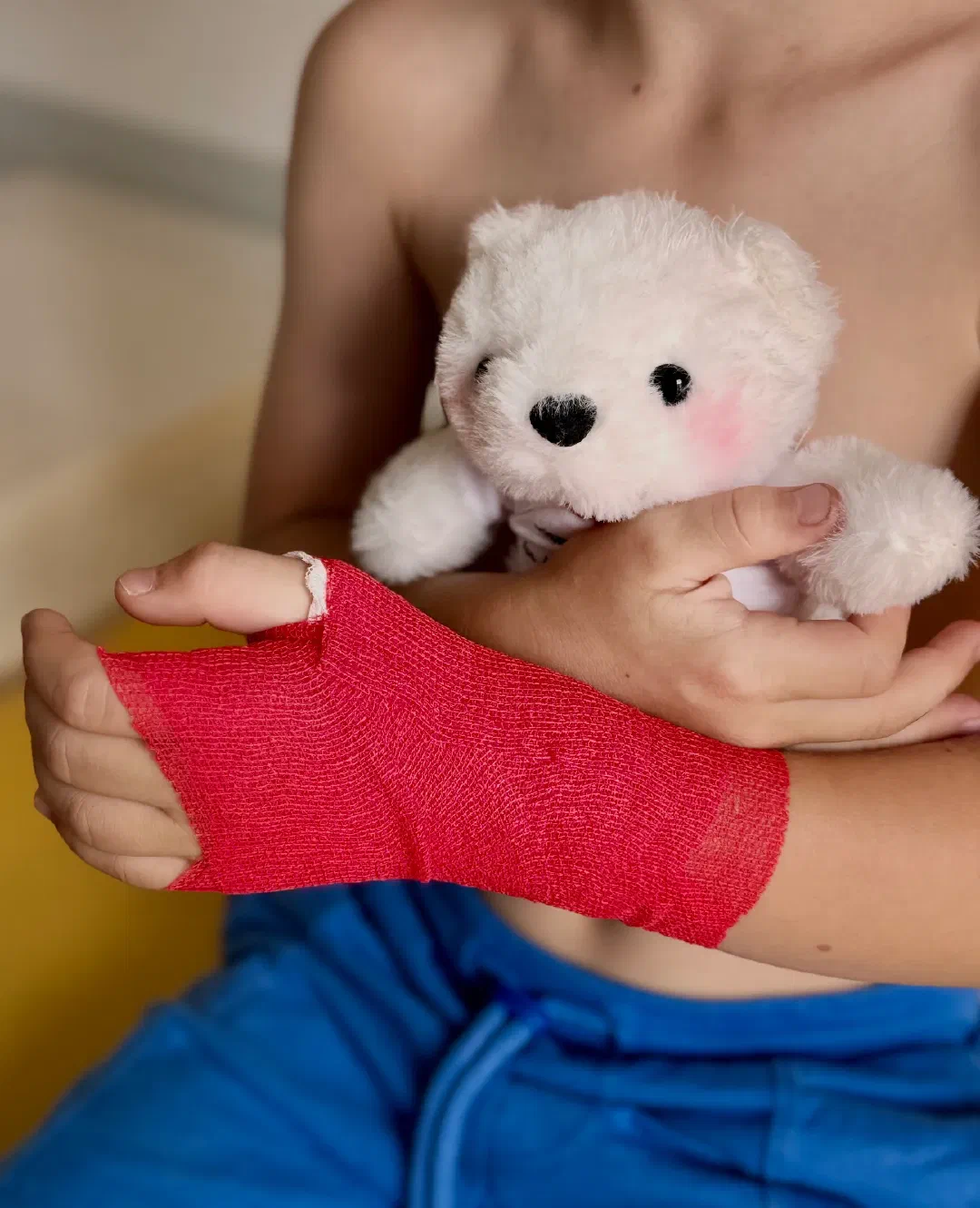 Kind mir Verband am Arm und Teddybär im Arm